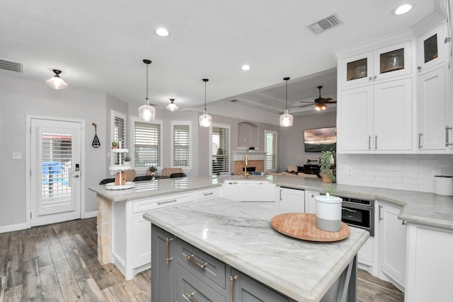 kitchen featuring kitchen peninsula, ceiling fan, hardwood / wood-style flooring, white cabinets, and a kitchen island