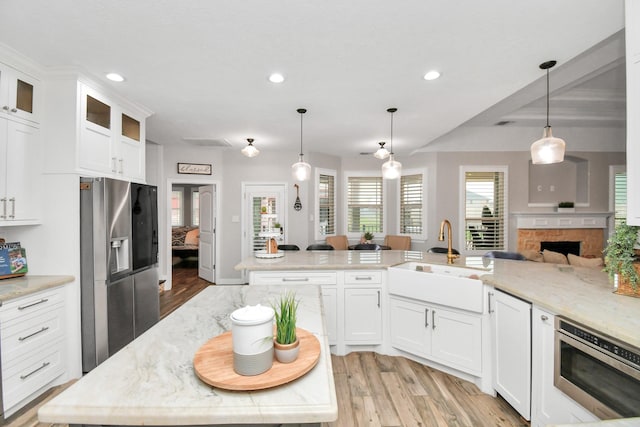 kitchen featuring white cabinetry, sink, light stone countertops, stainless steel fridge with ice dispenser, and decorative light fixtures