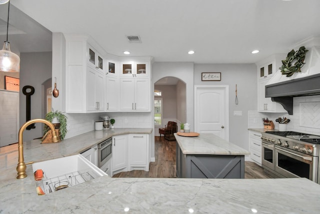 kitchen with sink, light stone counters, decorative light fixtures, white cabinets, and appliances with stainless steel finishes