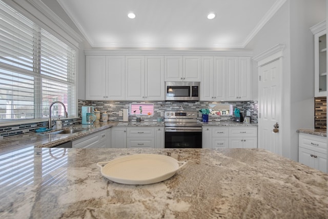 kitchen with appliances with stainless steel finishes, white cabinetry, crown molding, and sink