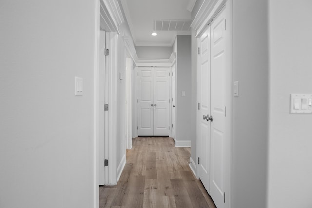 hall with ornamental molding and light hardwood / wood-style flooring