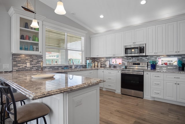 kitchen with kitchen peninsula, stainless steel appliances, white cabinetry, and hanging light fixtures