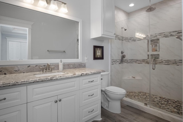 bathroom with hardwood / wood-style floors, vanity, an enclosed shower, and toilet