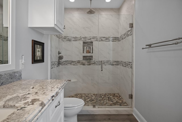 bathroom featuring toilet, vanity, an enclosed shower, and hardwood / wood-style flooring