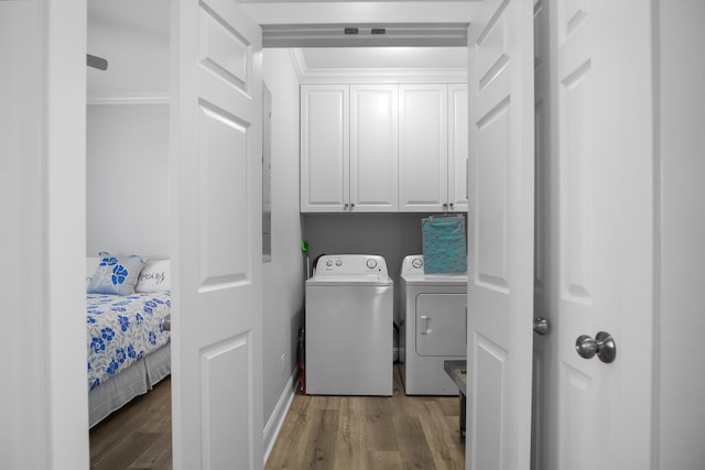 laundry room with cabinets, hardwood / wood-style flooring, washer and clothes dryer, and crown molding