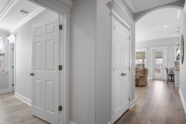 corridor featuring light wood-type flooring and ornamental molding