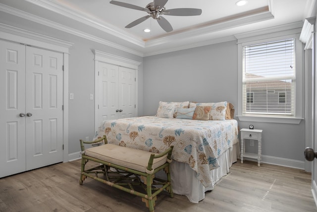 bedroom with ceiling fan, multiple closets, and a tray ceiling