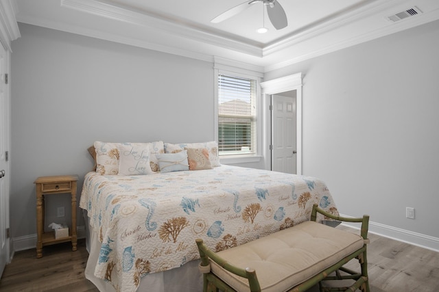 bedroom featuring a tray ceiling, ceiling fan, dark hardwood / wood-style floors, and ornamental molding