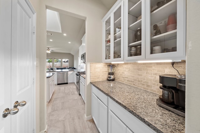 kitchen with white cabinets, appliances with stainless steel finishes, decorative backsplash, and light stone countertops