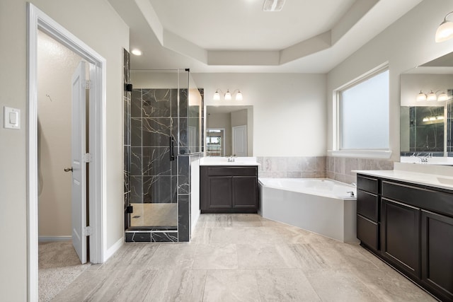 bathroom featuring a tray ceiling, vanity, and shower with separate bathtub