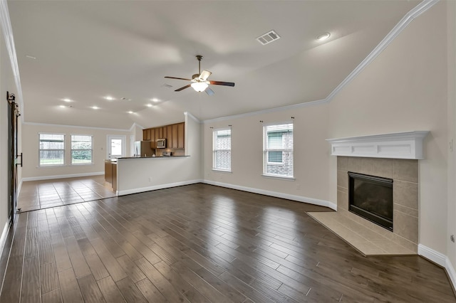 unfurnished living room featuring lofted ceiling, dark wood-type flooring, a wealth of natural light, and a tiled fireplace