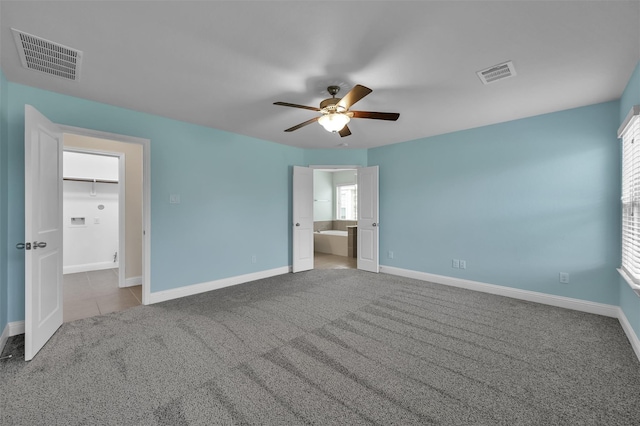 unfurnished bedroom featuring light colored carpet, ensuite bath, and ceiling fan