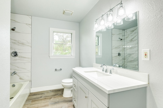 full bathroom with vanity, wood-type flooring, tiled shower / bath combo, and toilet