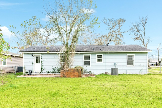 back of house with central AC and a lawn