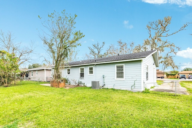 back of property with central air condition unit and a lawn