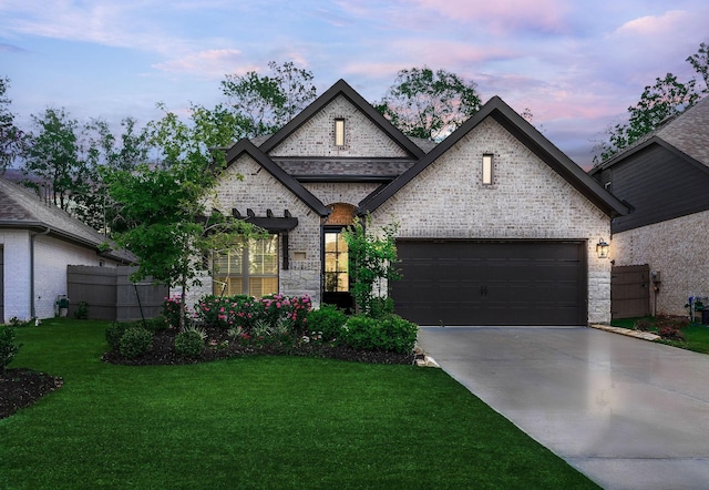 french country inspired facade featuring a garage and a yard