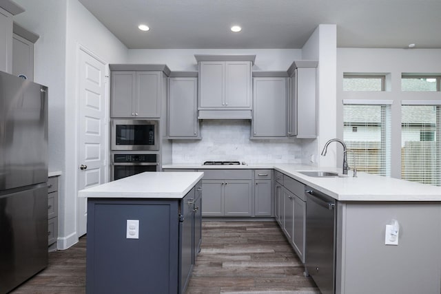 kitchen with tasteful backsplash, gray cabinetry, stainless steel appliances, sink, and a center island