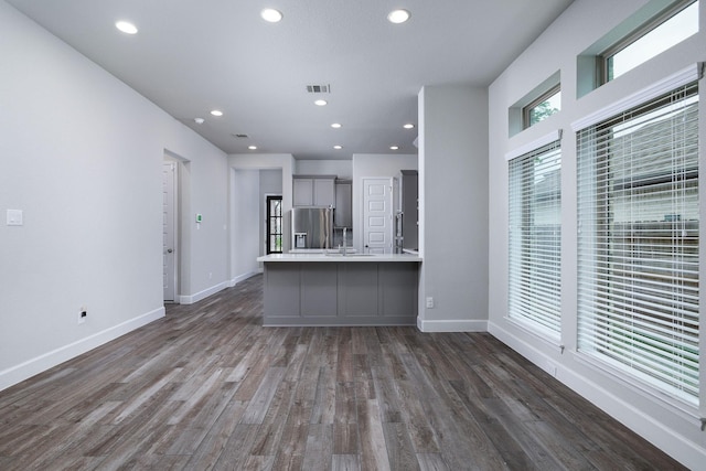 kitchen featuring stainless steel fridge, sink, dark wood-type flooring, and gray cabinetry