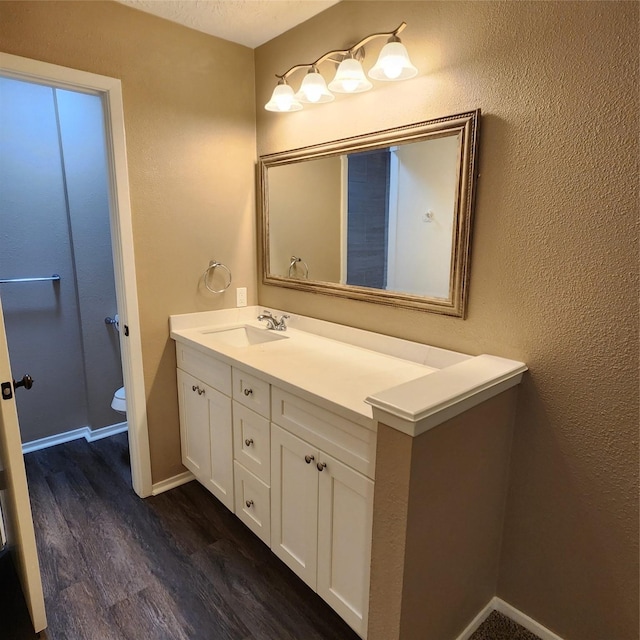 bathroom featuring wood-type flooring, vanity, and toilet