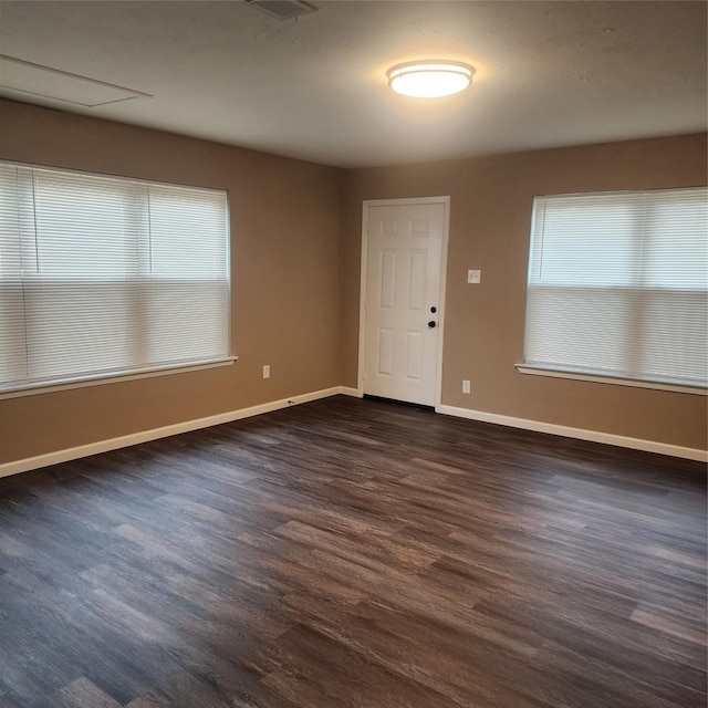 spare room with a wealth of natural light and dark hardwood / wood-style floors