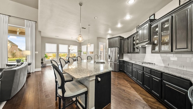 kitchen with appliances with stainless steel finishes, sink, a kitchen bar, decorative backsplash, and a center island with sink