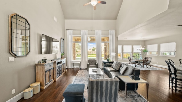 living room featuring dark wood-type flooring, ceiling fan with notable chandelier, and high vaulted ceiling