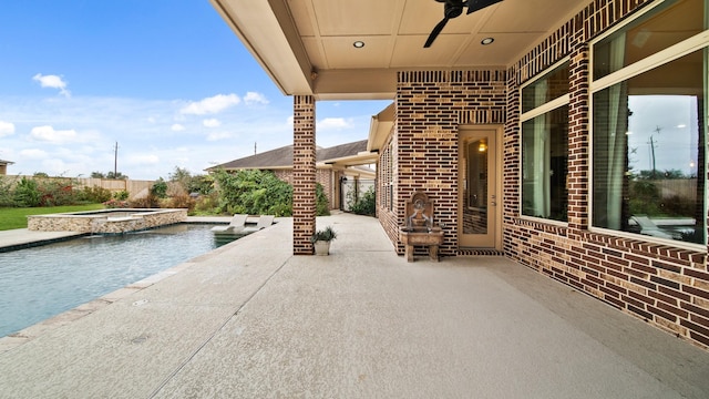 view of patio featuring ceiling fan and a swimming pool with hot tub