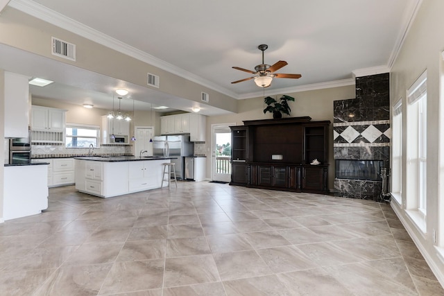 kitchen with backsplash, white cabinets, hanging light fixtures, appliances with stainless steel finishes, and a kitchen island