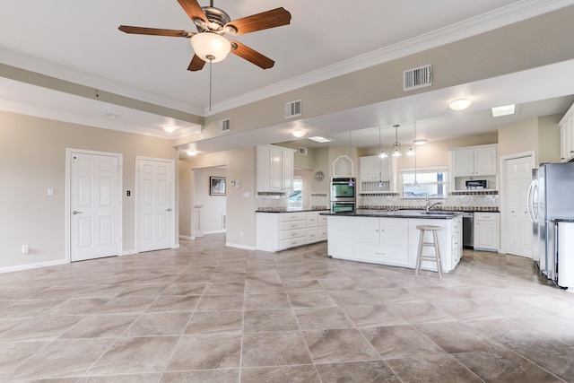 kitchen featuring white cabinetry, a center island, ceiling fan, stainless steel appliances, and decorative backsplash