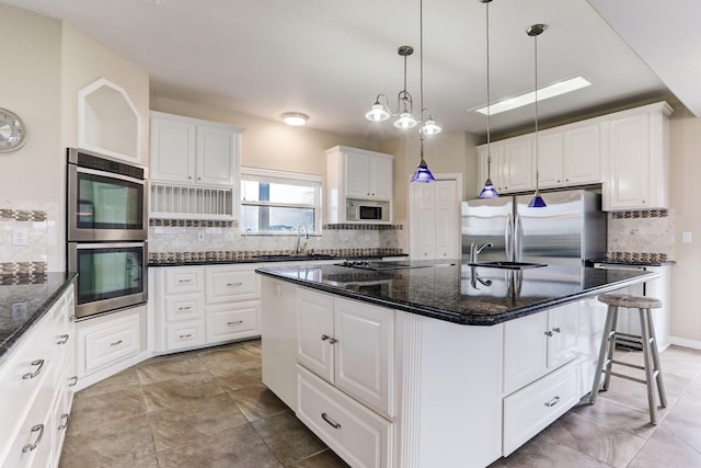 kitchen with white cabinets, backsplash, stainless steel appliances, and a kitchen island with sink