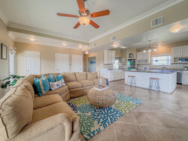 living room with a textured ceiling, ceiling fan, ornamental molding, and sink