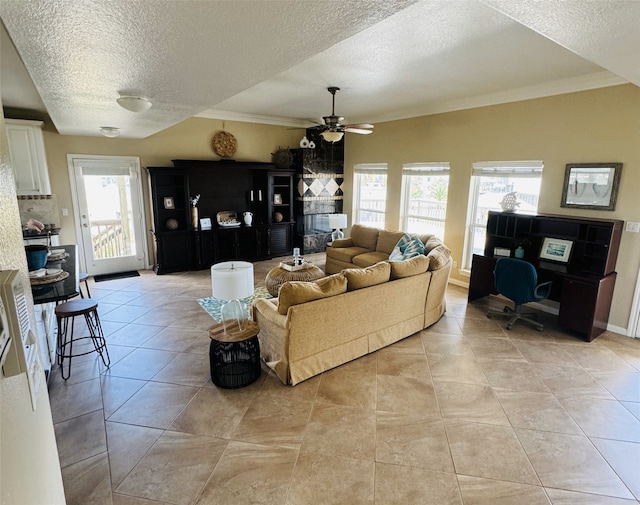 tiled living room with a textured ceiling, ceiling fan, and ornamental molding