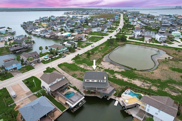 aerial view at dusk featuring a water view