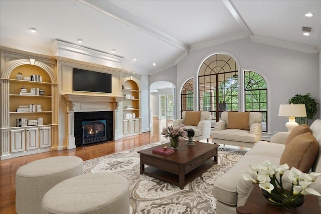 living room featuring plenty of natural light, built in features, crown molding, and a tile fireplace