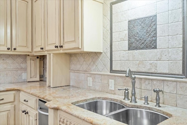 kitchen with tasteful backsplash, cream cabinets, light stone countertops, and sink