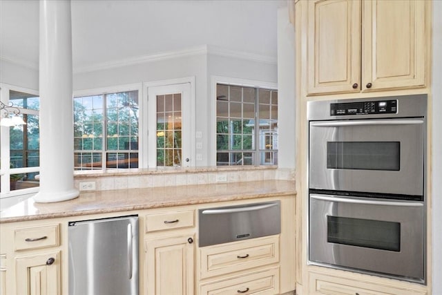 kitchen featuring refrigerator, ornate columns, double oven, crown molding, and cream cabinets