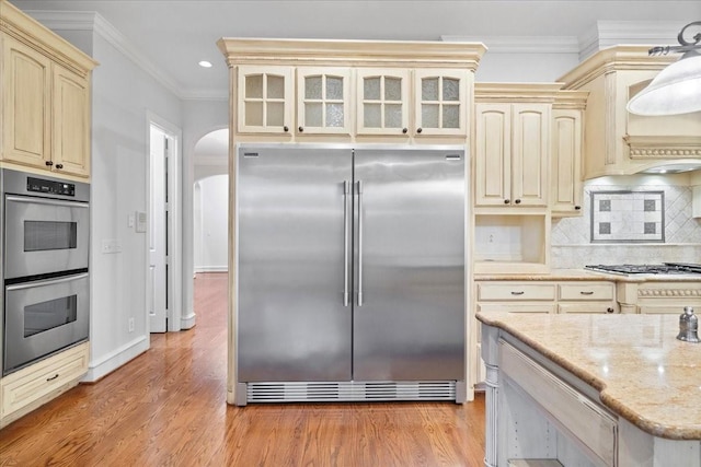 kitchen featuring cream cabinetry, decorative backsplash, stainless steel appliances, and crown molding