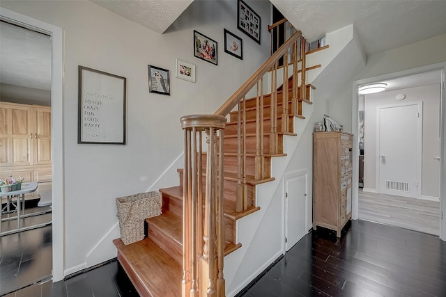 staircase with hardwood / wood-style floors and a textured ceiling