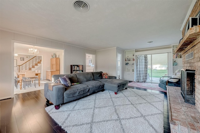 living room featuring hardwood / wood-style flooring, built in features, a fireplace, and a chandelier