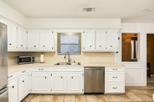 kitchen with white cabinets, light tile patterned floors, stainless steel appliances, and sink