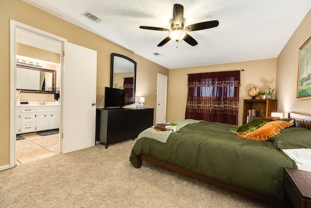 bedroom with ensuite bath, ceiling fan, light carpet, and a textured ceiling