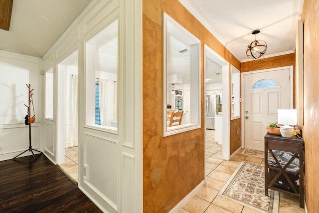 foyer featuring light tile patterned floors, an inviting chandelier, and crown molding