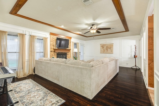 living room featuring dark hardwood / wood-style floors, a brick fireplace, ceiling fan, and ornamental molding