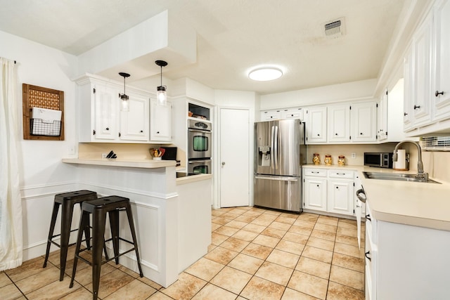 kitchen with pendant lighting, sink, light tile patterned floors, white cabinetry, and stainless steel appliances