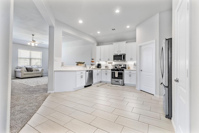 kitchen featuring white cabinetry, ceiling fan, light colored carpet, and appliances with stainless steel finishes