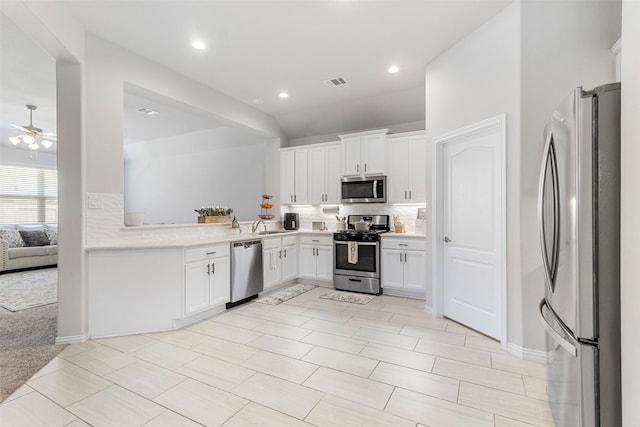 kitchen featuring decorative backsplash, appliances with stainless steel finishes, light carpet, ceiling fan, and white cabinets