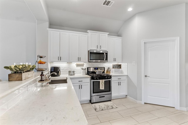 kitchen featuring white cabinets, sink, tasteful backsplash, light stone counters, and stainless steel appliances