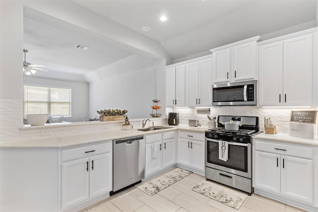 kitchen with white cabinets, kitchen peninsula, appliances with stainless steel finishes, and tasteful backsplash