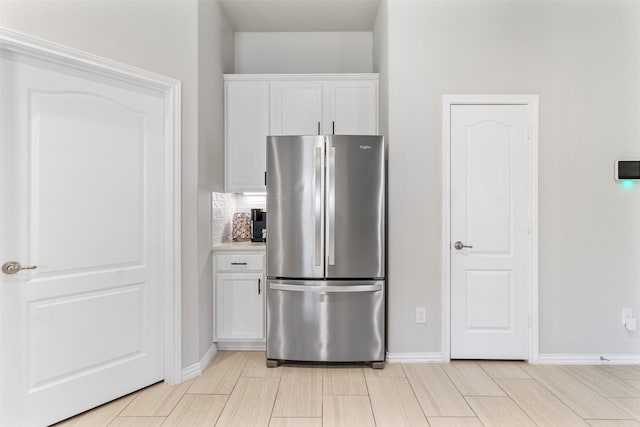 kitchen with white cabinets, backsplash, and stainless steel refrigerator