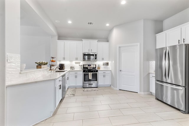 kitchen with decorative backsplash, kitchen peninsula, stainless steel appliances, sink, and white cabinets